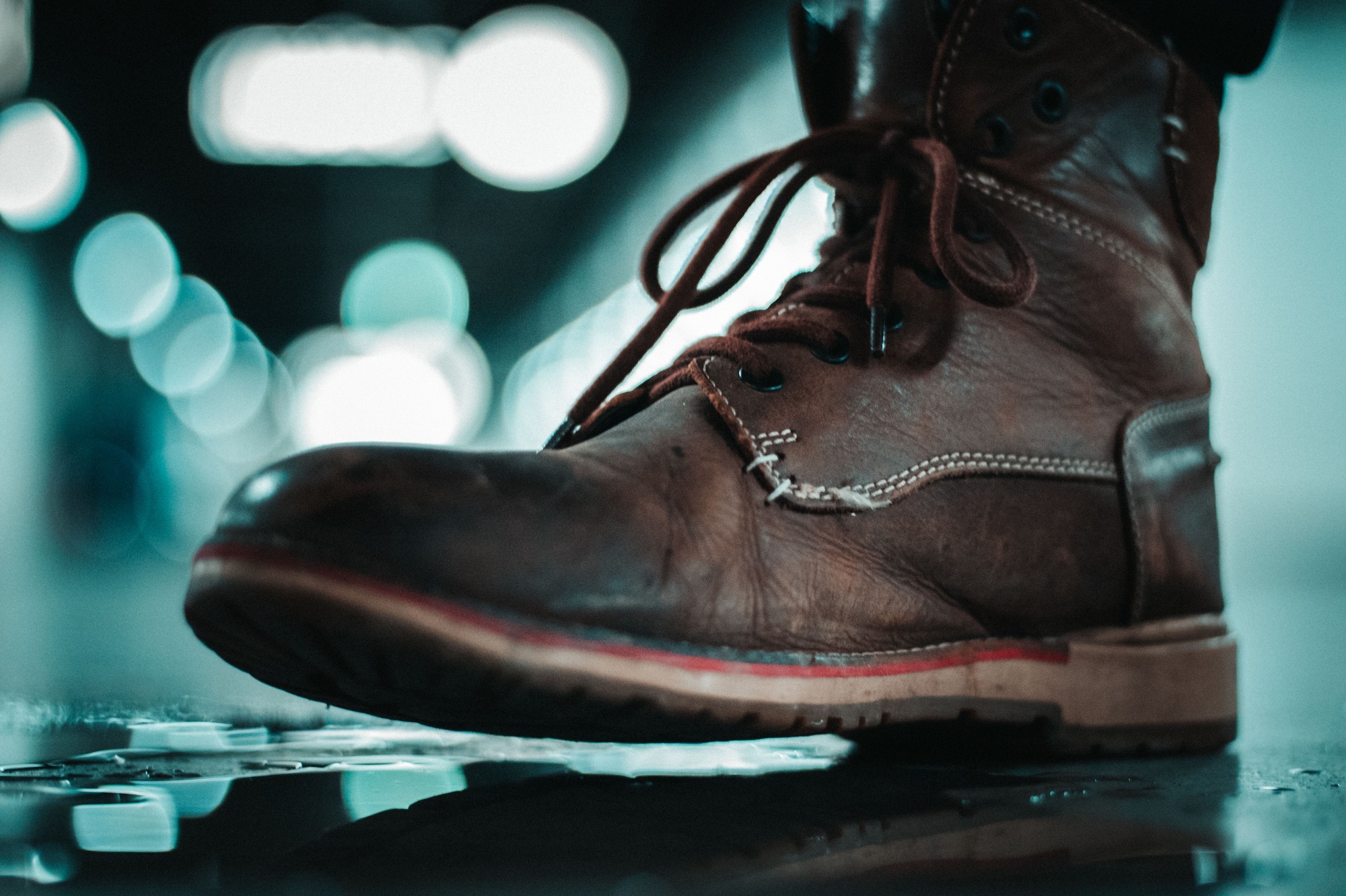 Closeup of a brown, worn out and dirty man's boot on the ground